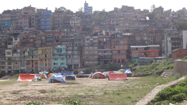 キルティプール市外観（山肌にこぼれんばかりに建つ家々と広場でテントを張り避難する人々）